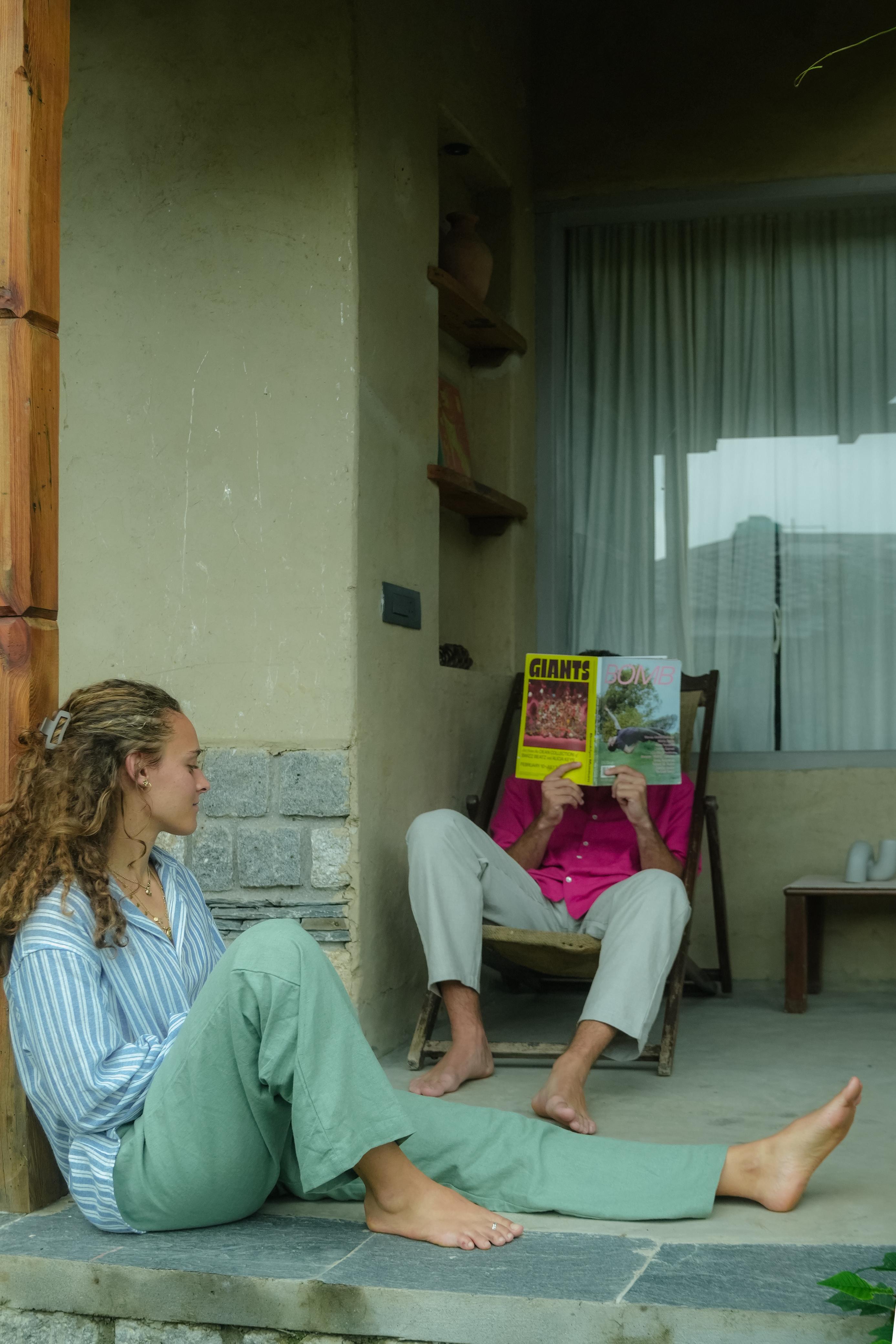 Two people sitting on a stone ledge with one reading a book titled 'Giant's'.